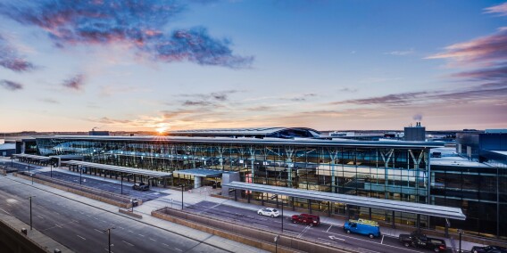 Wide exterior view of a modern airport terminal at sunset.