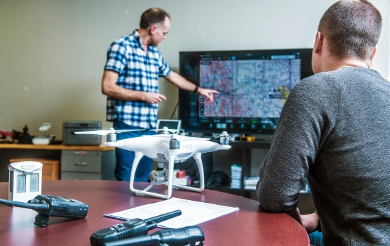 Two people review a map on a screen during a drone operations meeting.