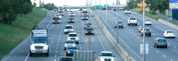 Cars and trucks traveling on a multi-lane divided highway during daylight.