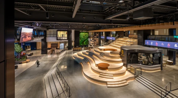 Large modern office atrium with tiered seating, wide walkways, and illuminated interior design.