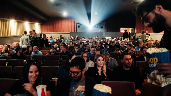 Audience members seated in a movie theater while popcorn is served before the screening.