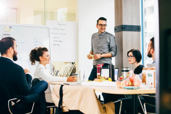 Office team gathered around a whiteboard during a standup meeting and presentation.