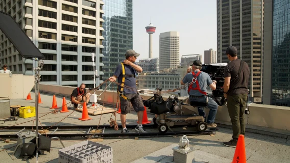 Film crew working on a rooftop in downtown Calgary with the Calgary Tower visible in the background.