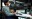 Video editor working at a dual-monitor desk with editing software open in a modern office.