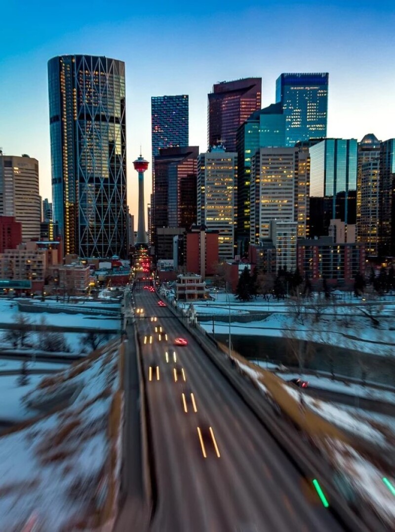 Aerial view of downtown Calgary in winter with illuminated streets and snowy foreground.