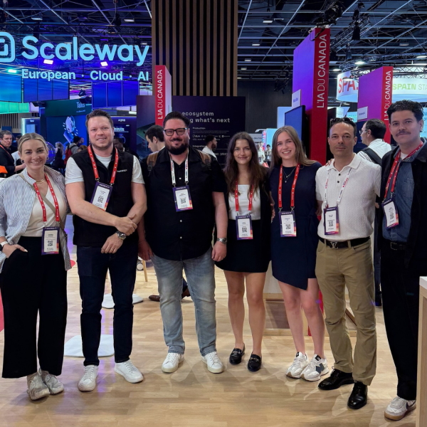 Seven people wearing red lanyards stand side-by-side smiling.
